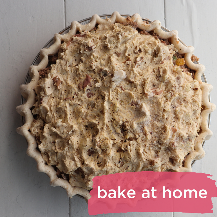 A pie with a pastry crust topped with red potato mash with a "Bake at Home" banner along the bottom